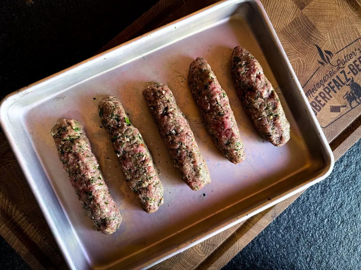 Geformte rohe Adana Sticks aus Rinderhack auf dem Blech