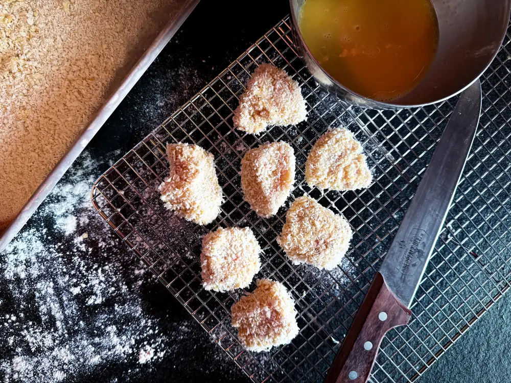 Panierte Hähnchenstücke auf dem Gitter vor dem Frittieren