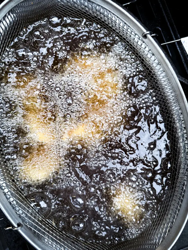 Hähnchenstücke im Frittierkorb im heißen Öl