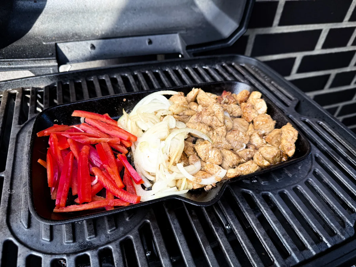 Hähnchenstreifen, Zwiebeln und Paprika auf der Plancha im Grill