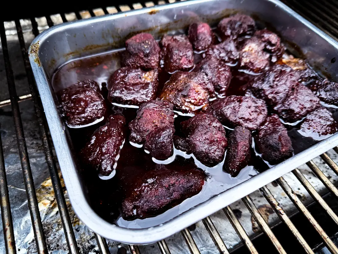 Burnt Ends in BBQ-Sauce in der Aluschale auf dem Smoker