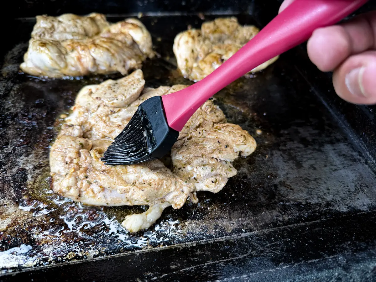 Frango Churrasco wird auf der Plancha mit Marinade bestrichen