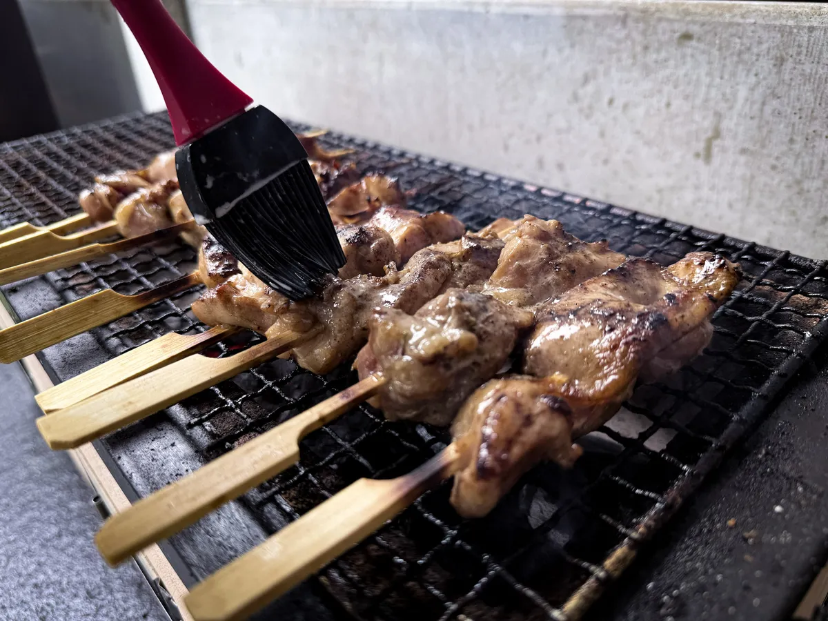 Gai Ping wird auf dem Holzkohlegrill mit Kokosmilch bestrichen