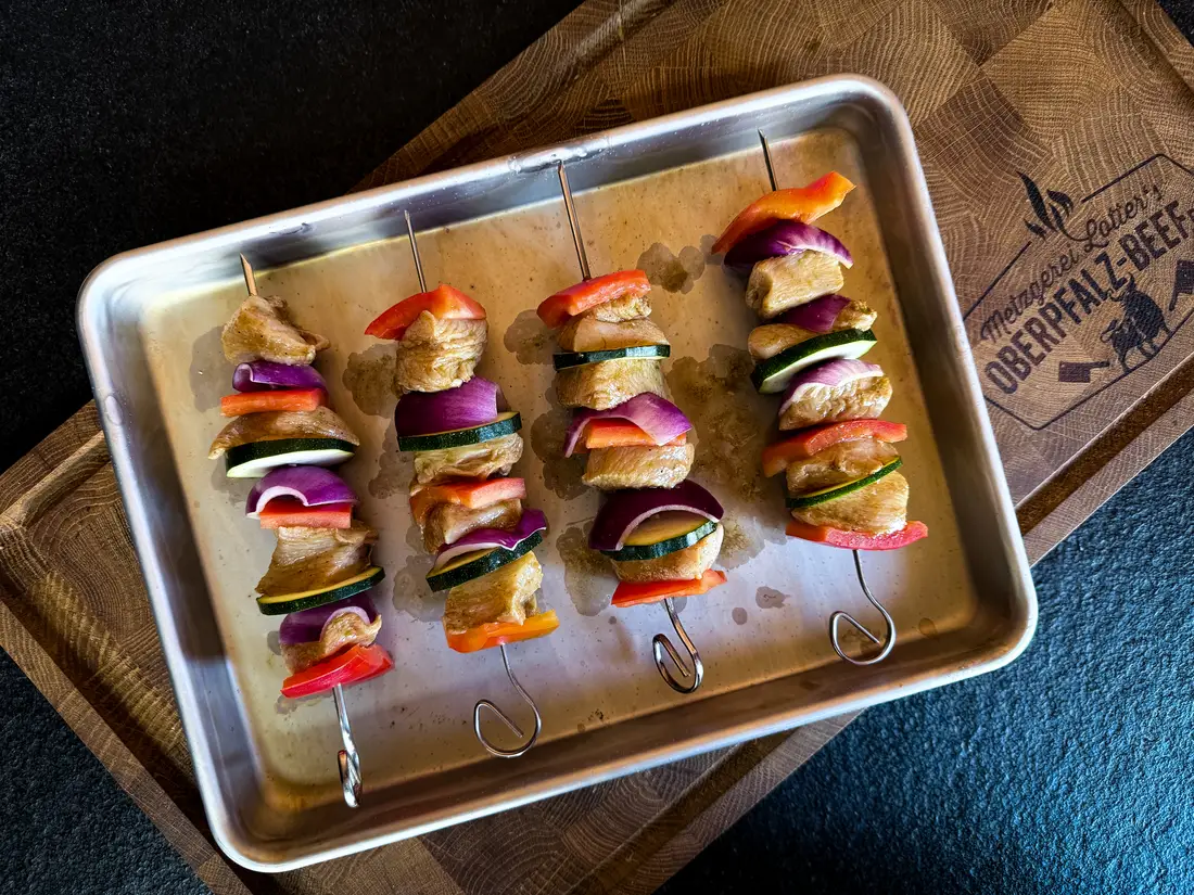 Rohe Hähnchenspieße mit Paprika, Zucchini und roter Zwiebel auf dem Blech