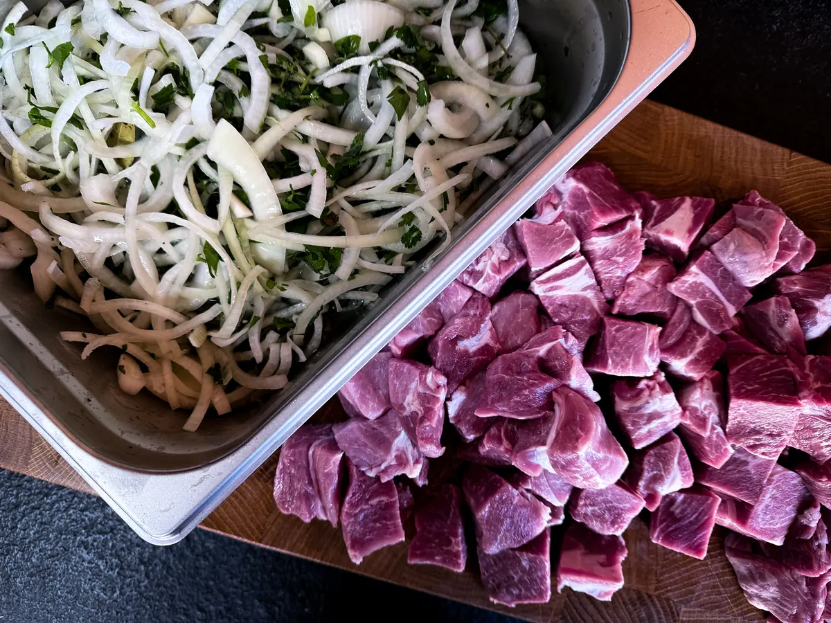 Schweinenacken in Würfeln und Zwiebelringe für die Marinade