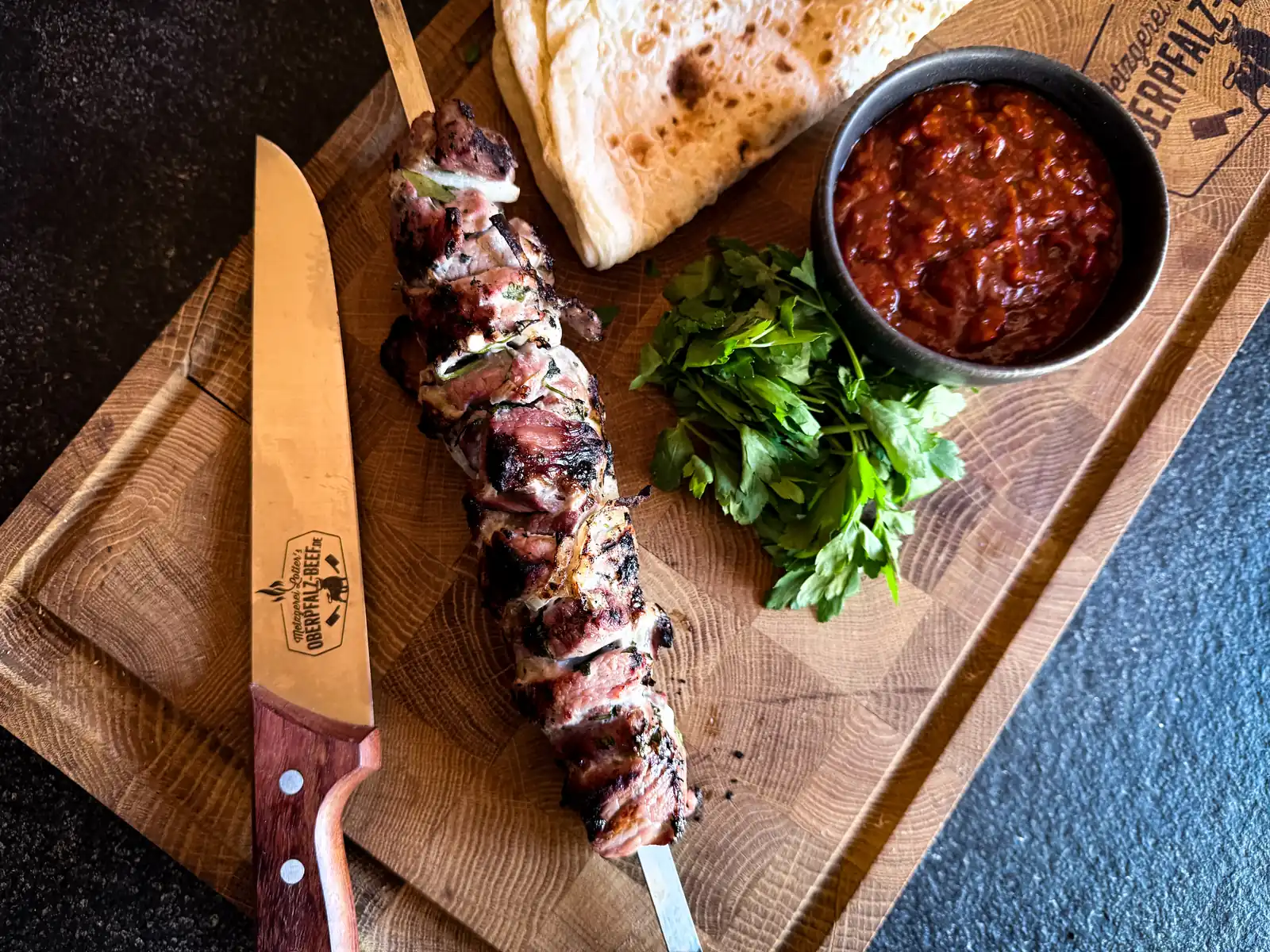 Gegrillter Schaschlik-Spieß mit Fladenbrot, Kräutern und Tomatensauce