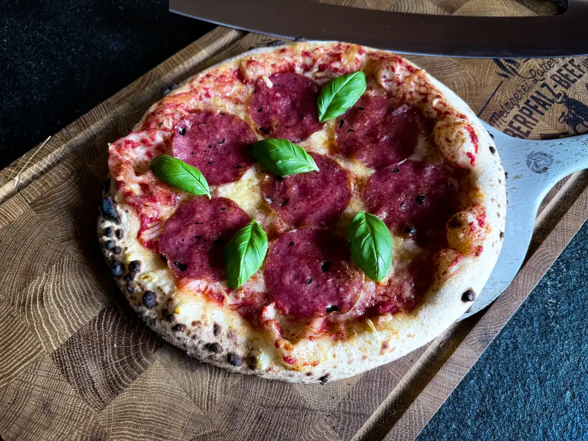 Trüffel-Salami-Pizza mit Basilikum auf dem Holzbrett
