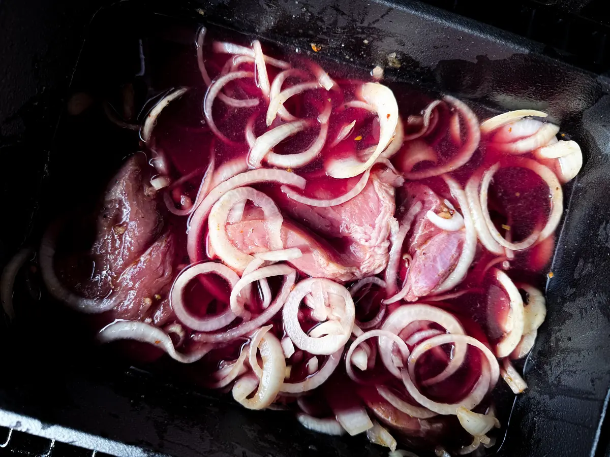 Schweinenacken mit Zwiebelringen vor dem Schmoren