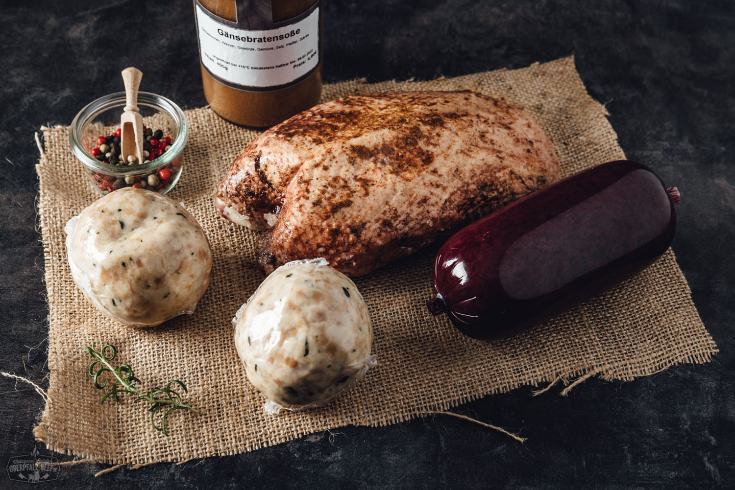 Goldbraun gebratene Gänsebrust mit knuspriger Haut auf rustikalem Holzbrett, serviert mit dunkelbrauner Bratensauce, dazu Preiselbeeren und frischer Rosmarin – traditionelle Oberpfälzer Gänsebox, appetitlich angerichtet für das Weihnachtsessen.