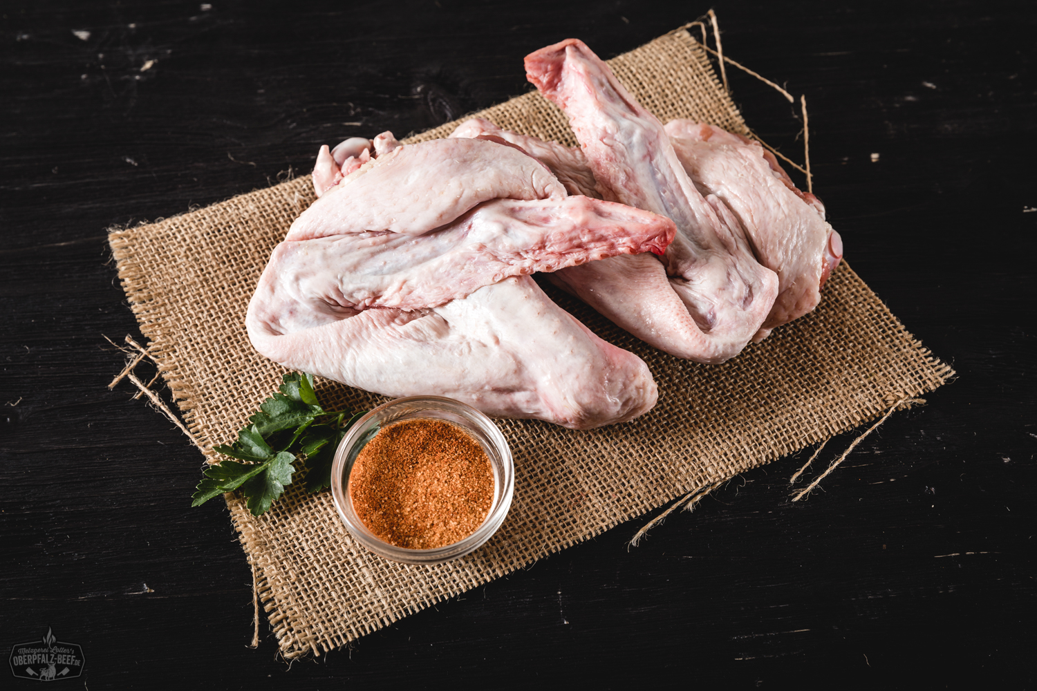 Rohes, küchenfertig portioniertes Entenfleisch von der Oberpfälzer Bauernente auf einem dunklen Untergrund, garniert mit frischen Kräutern, Pfefferkörnern und grobem Salz – hochwertige Fleischqualität aus regionaler Herkunft für bewussten Fleischgenuss.