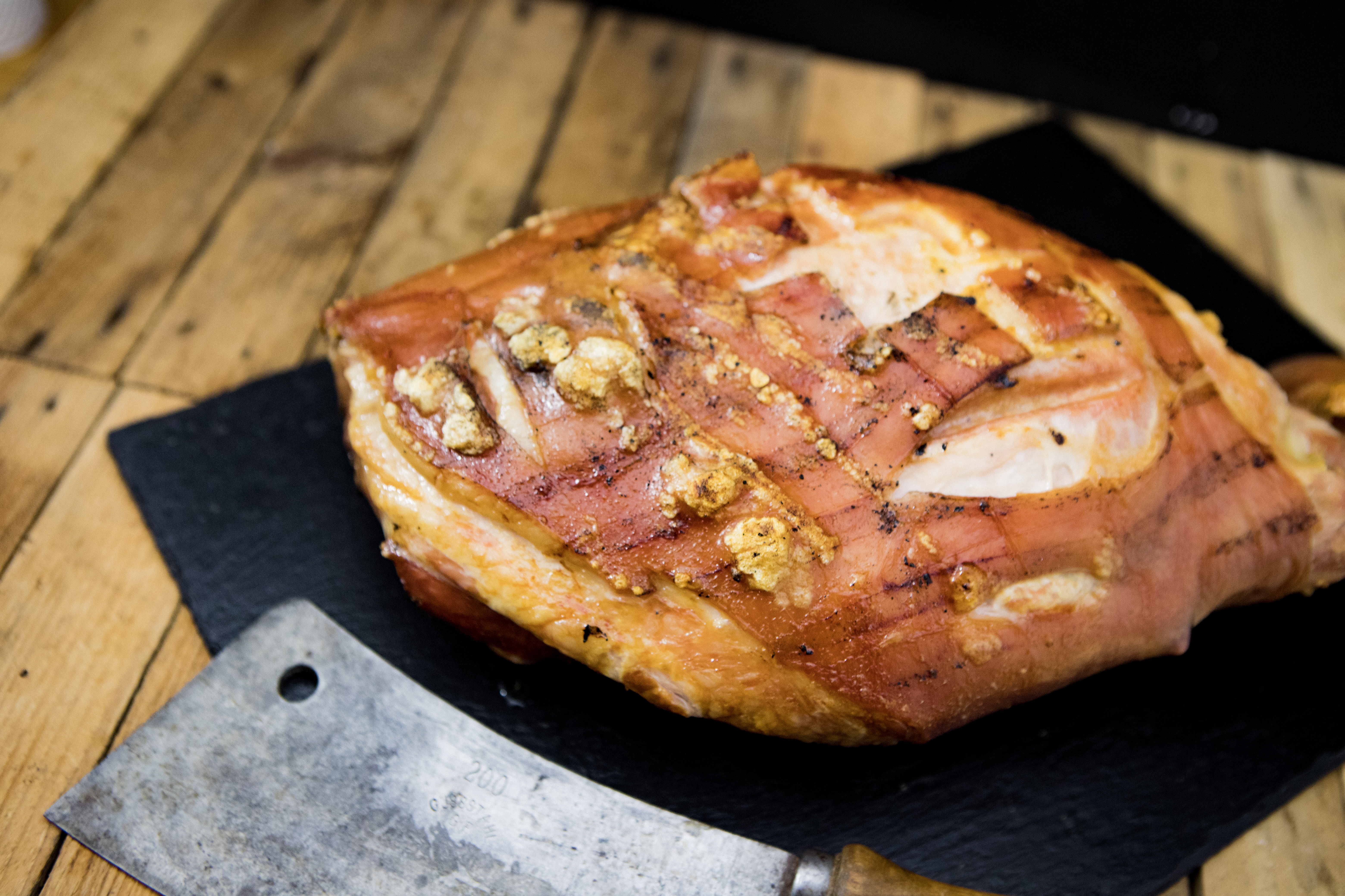 Spanferkelkeule vom Oberpfälzer Landschwein knusprig gebraten auf Holzbrett – regionales BBQ-Fleischgericht Spanferkelkeule vom Oberpfälzer Landschwein – goldbraun knusprig gebraten, saftig tranchiert und auf einem Holzbrett angerichtet, mit frischen Kräutern garniert; traditionelles bayerisches Fleischgericht in hochwertiger Qualität.
