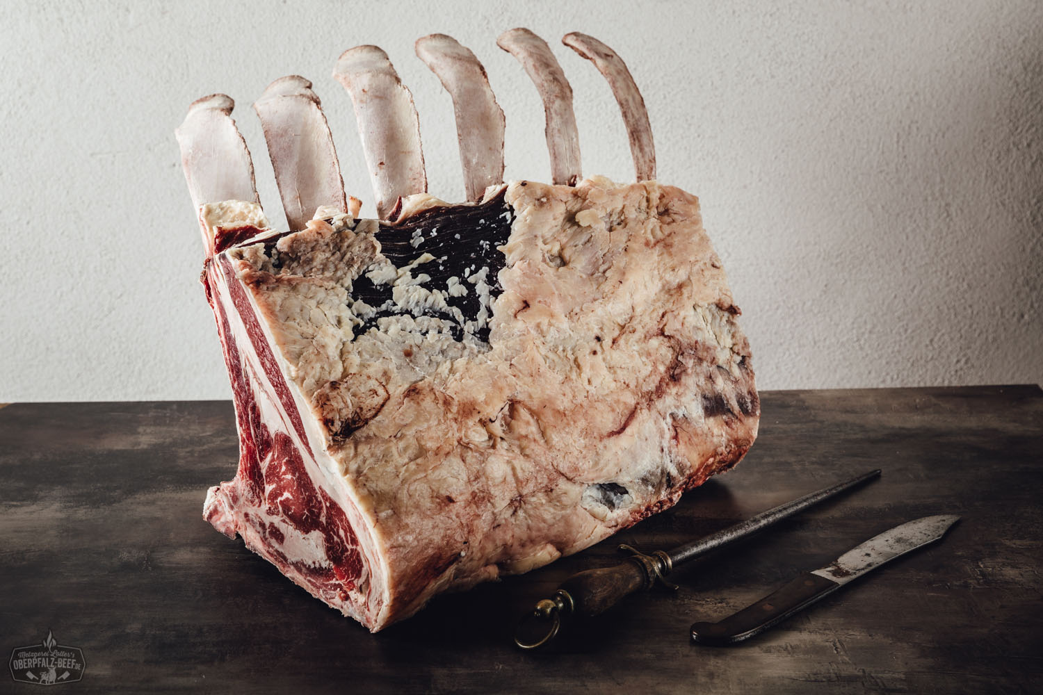 Rohes Tomahawk-Steak vom Oberpfalz-Rind auf dunklem Untergrund, mit sichtbarem langen Knochen und gut marmorierter Fleischstruktur, ideal zum Reifen oder Grillen.