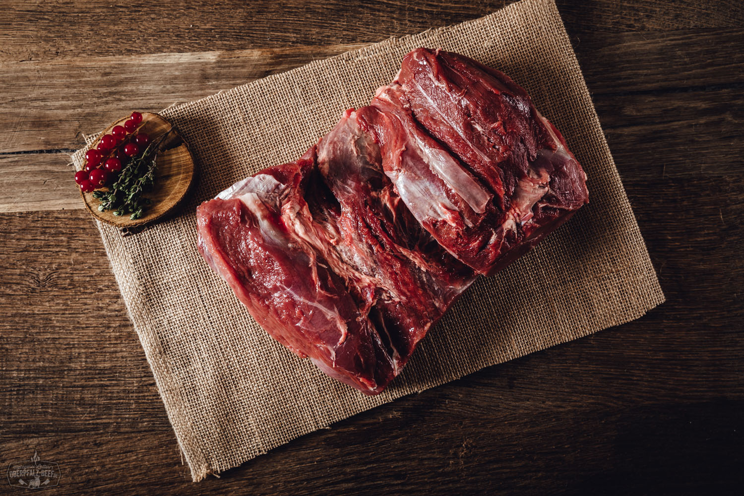 Braten vom Oberpfälzer Wildschwein, saftig aufgeschnitten und angerichtet auf einem Holzbrett – dekoriert mit frischen Kräutern und Pfefferkörnern, im Hintergrund rustikale Tischdekoration mit herbstlichem Flair.