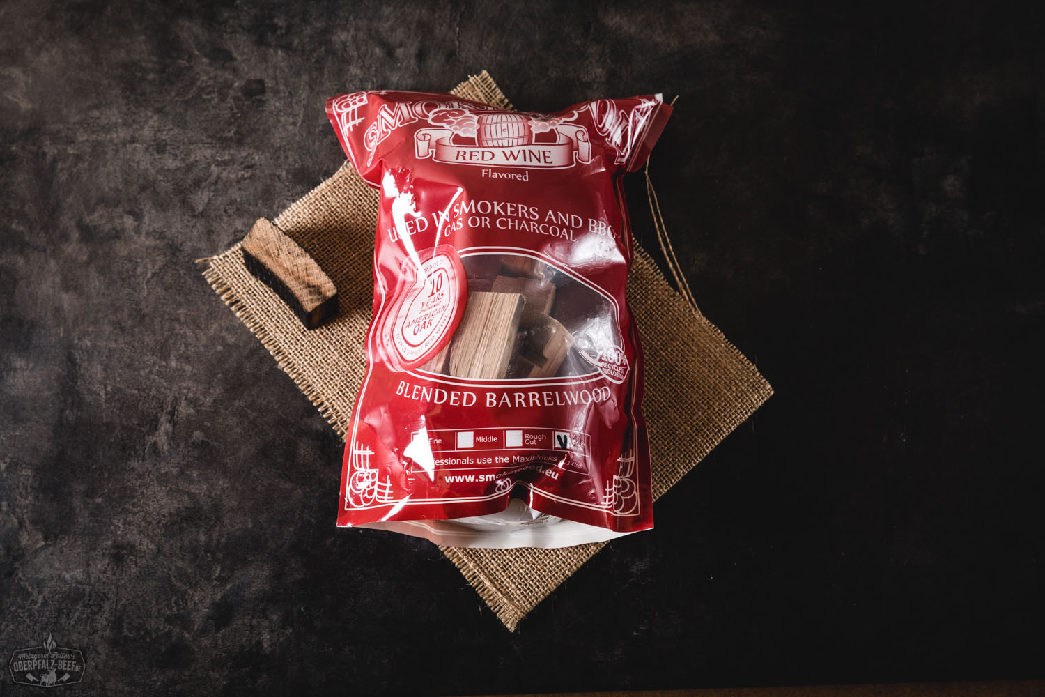 Kleine, rechteckige Mini-Blocks aus Rotwein-gedämpftem Räucherholz (Smokewood), ordentlich auf einem Holzbrett arrangiert, mit sichtbarer Holzmaserung; ideal zum Räuchern von Fleisch wie Beef oder BBQ – Produktfoto mit rustikalem Hintergrund.