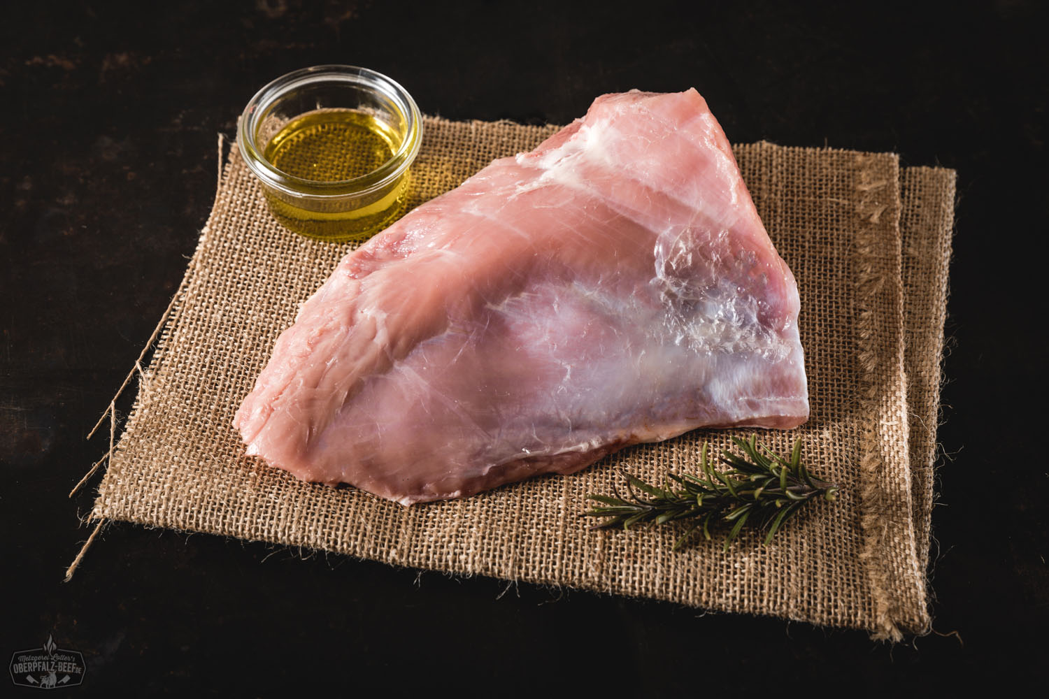 Tafelspitz vom Oberpfälzer Milchkalb – zartes Kalbfleisch in Premiumqualität Roher Tafelspitz vom Oberpfälzer Milchkalb auf dunklem Untergrund, saftig marmoriert, umgeben von frischen Kräutern, Knoblauch und Gewürzen – hochwertiges Kalbfleisch für feine Fleischgerichte.