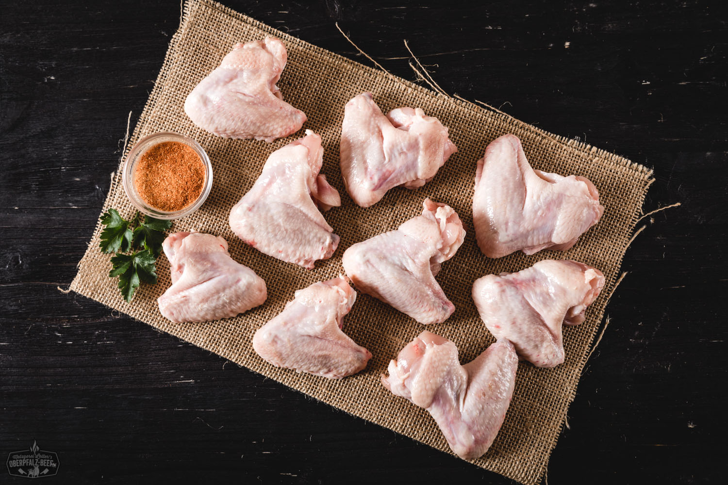 Gegrillte Chicken Wings vom Oberpfälzer Bauernhähnchen, knusprig gebräunt und saftig angerichtet auf einem rustikalen Schneidebrett mit frischen Rosmarinzweigen – hochwertiges Geflügelfleisch aus regionaler Aufzucht.