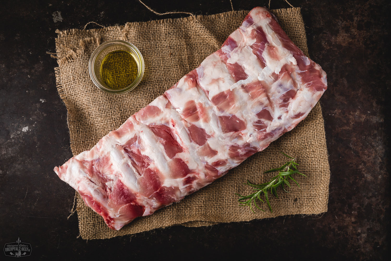 Ribs vom Oberpfälzer Milchkalb auf Holzbrett – zartes Fleischgericht für BBQ-Fans Zart gegrillte Rinder-Rippchen vom Oberpfälzer Milchkalb auf einem rustikalen Holzbrett angerichtet, umgeben von Rosmarinzweigen und Meersalz, im Hintergrund ein dunkler Untergrund für starken Kontrast – ideal für BBQ und Feinschmecker.