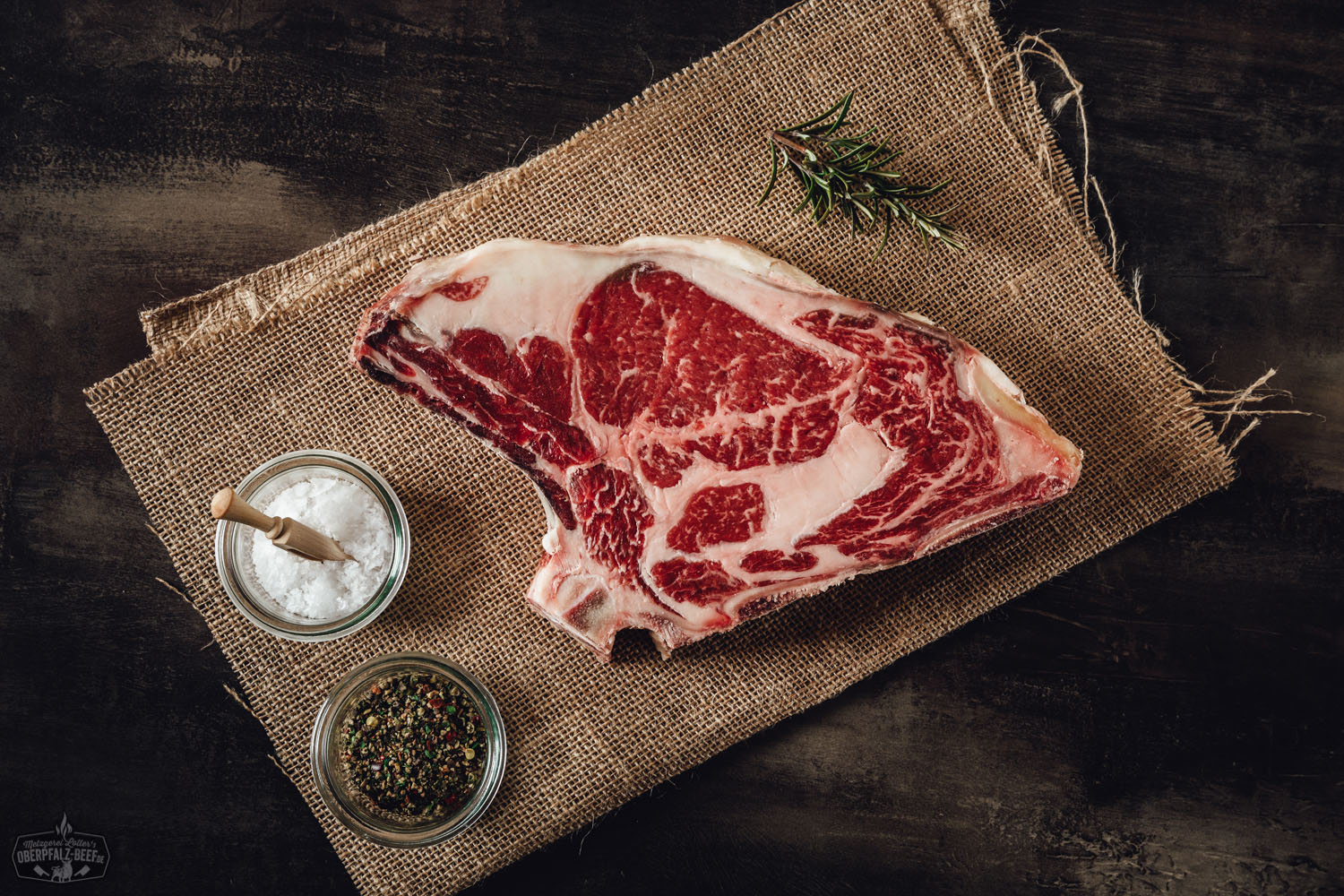 Dry Aged Entrecôte mit Knochen – Premium Rib-Eye Steak vom Rind Dry Aged Entrecôte Rib-Eye am Knochen auf dunklem Untergrund; das marmorierte Rindfleisch weist eine kräftige rote Farbe und feine Fettäderchen auf, ideal zur Zubereitung als Steak – hochwertiges Premiumfleisch für echte Fleischliebhaber.