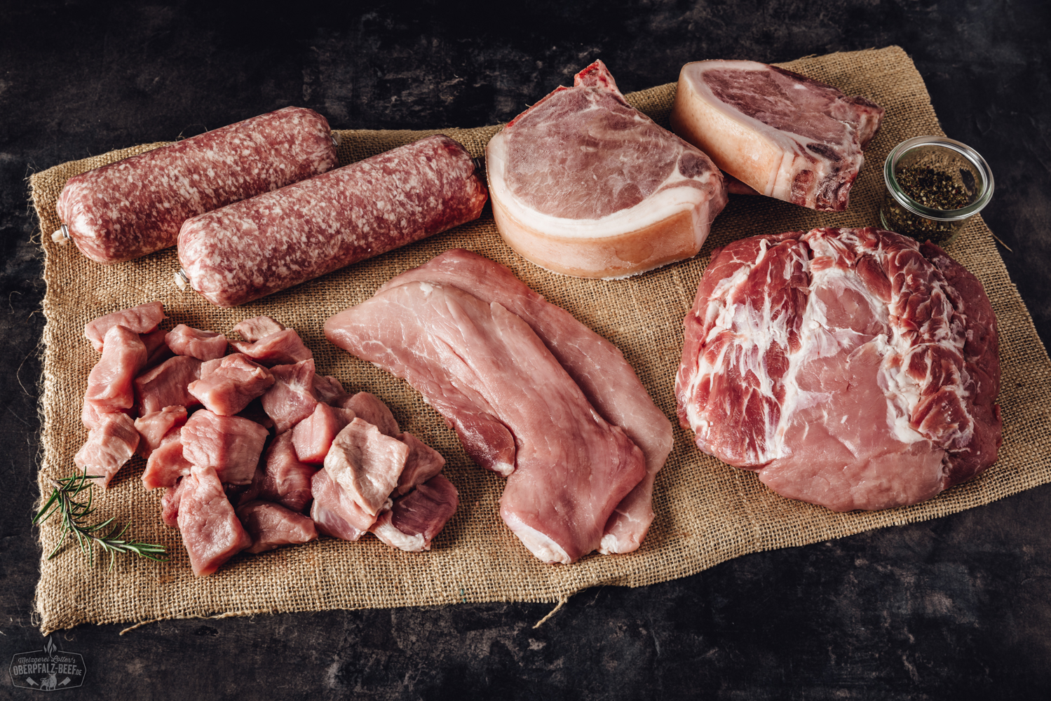 Frisch verpacktes Schweinefleisch aus artgerechter Haltung in einer offenen Bauernhof-Box auf Holztisch, mit regionalem Qualitätsfleisch, etikettierten Stücken und natürlichem Hintergrund – ideal für nachhaltigen Fleischgenuss.