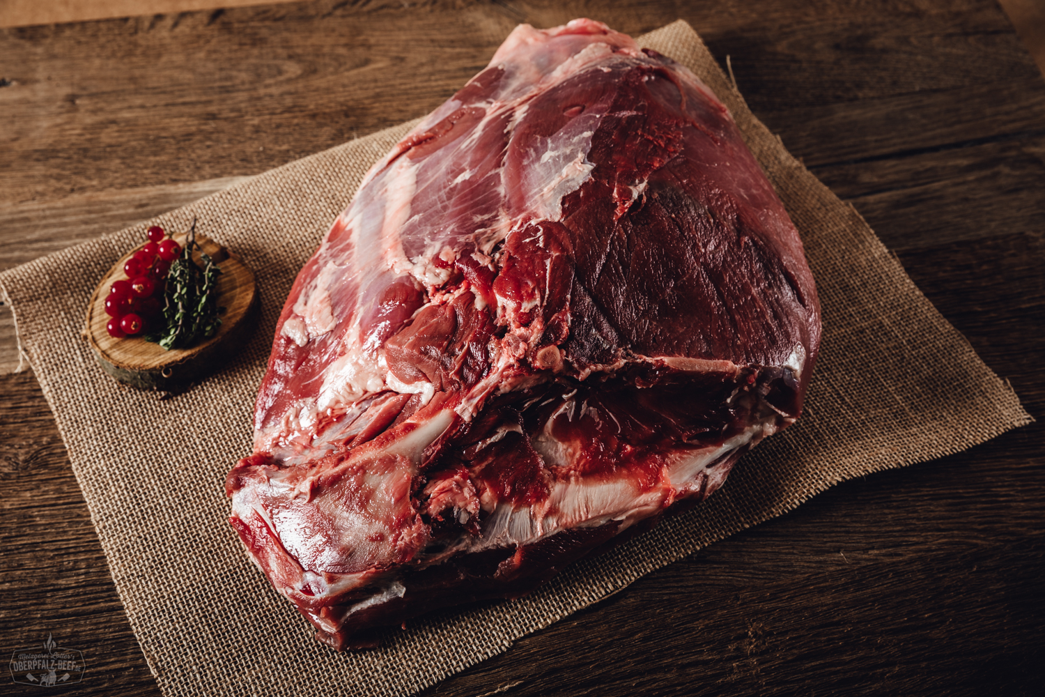 Wildschweinkeule mit Knochen vom Oberpfälzer Wild – Frischfleisch für Braten und Grill Rohe Keule mit Knochen vom Oberpfälzer Wildschwein auf dunklem Untergrund, umgeben von frischen Kräutern wie Rosmarin und Thymian sowie grobem Meersalz und Pfeffer – hochwertiges Wildfleisch aus regionaler Jagd.