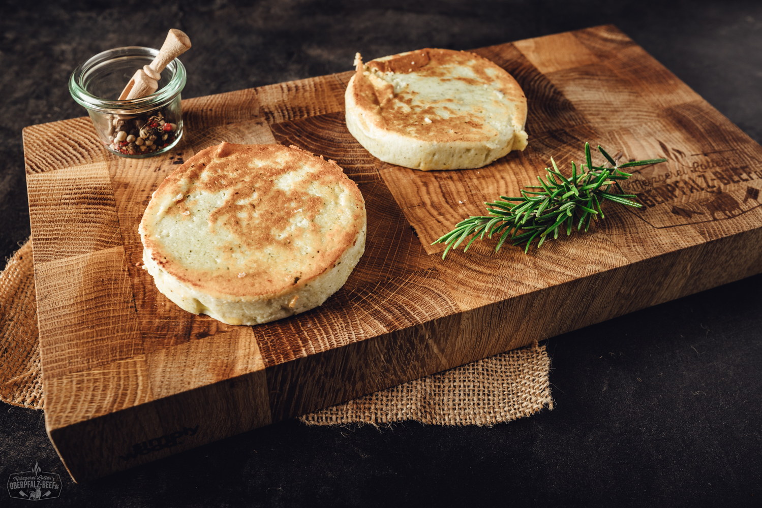 Grillkäse mit Kräutern auf Holzteller – vegetarische Grillalternative Gegrillter Grillkäse mit goldbrauner Kruste, serviert auf dunklem Holzbrett neben roten Peppadew-Chili-Schoten, frischen Kräutern und Meersalz – hochwertige Nahaufnahme für BBQ und vegetarische Grillrezepte.