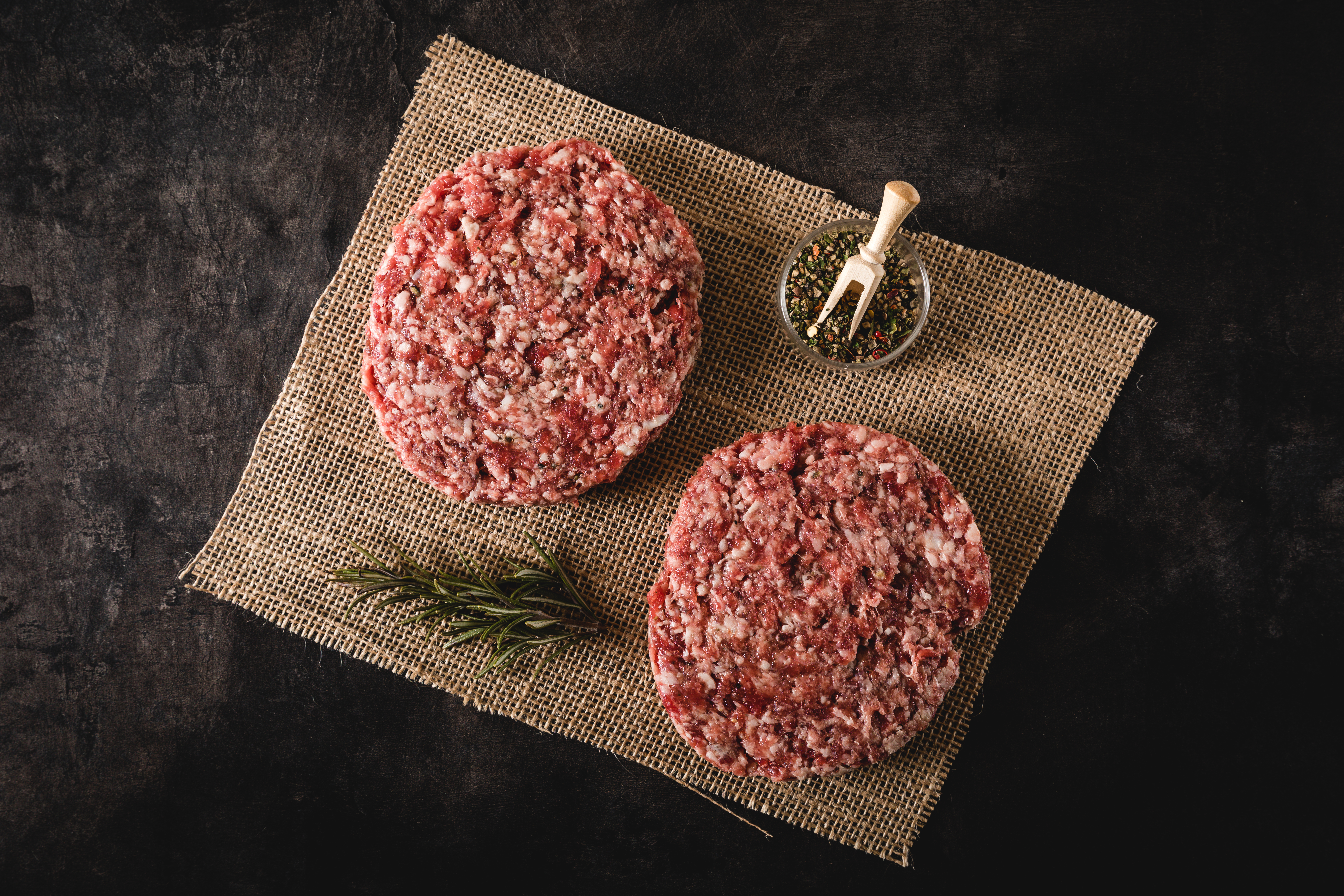 Dry Aged Beef Patties auf Holzbrett – Hochwertiges Oberpfalz-Rindfleisch Dry Aged Beef Patties auf schwarzem Grillrost mit Grillspuren und saftigem Inneren, perfekt für Burger Liebhaber. Hochwertiges Rindfleisch, ideal für kulinarische Grillerlebnisse und BBQs.