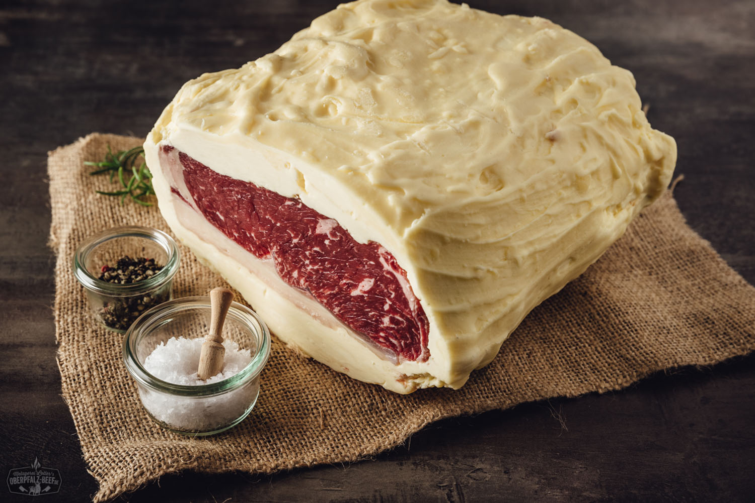 Roastbeef am Stück, buttergereift: Großes, saftig marmoriertes Rindfleischstück in Nahaufnahme auf schwarzem Hintergrund, roh und frisch mit sichtbarer Fettstruktur – ideal für Fleischliebhaber, Dry Aged Beef Fans und Premium-Steak-Zubereitung.