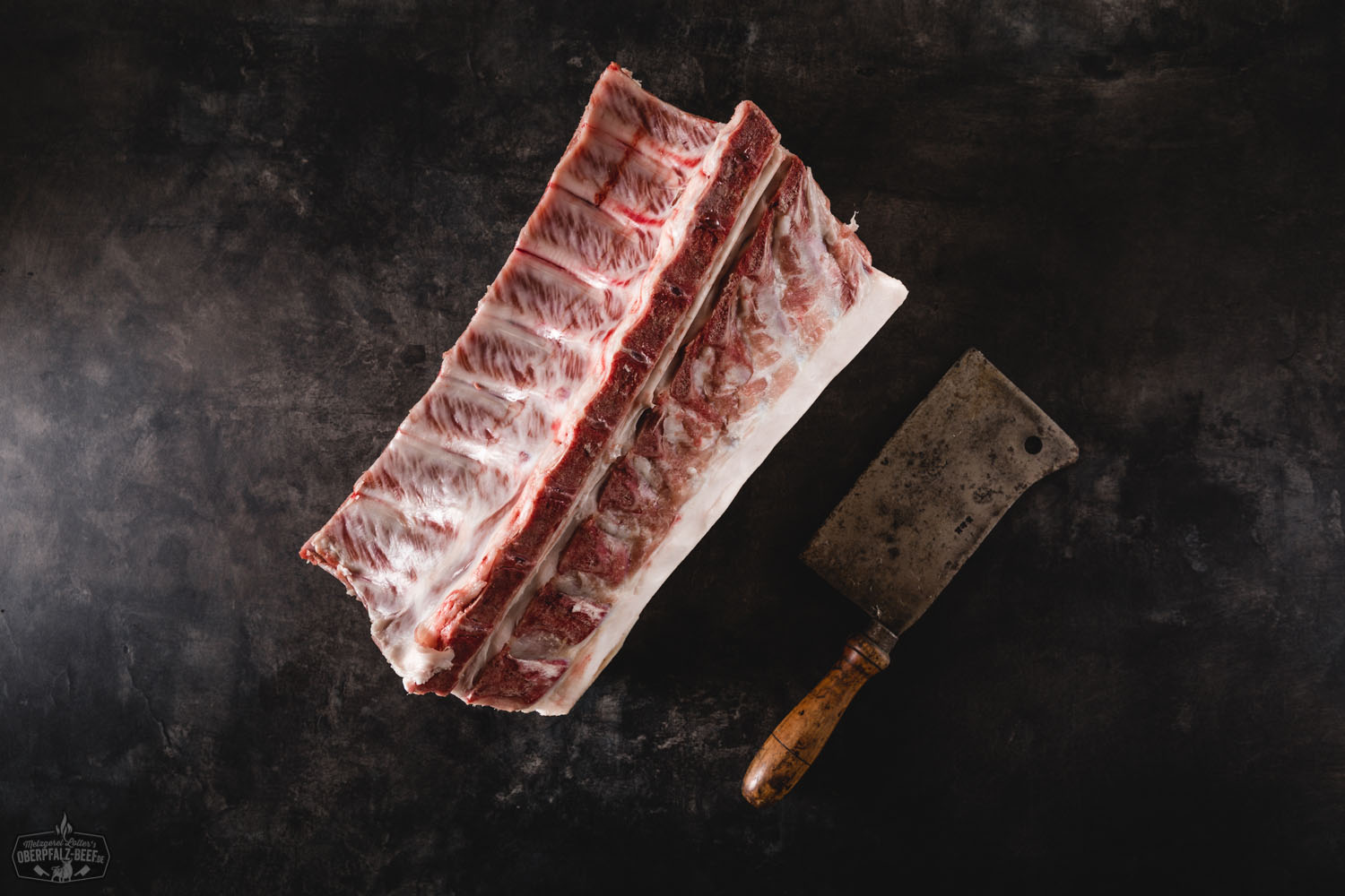 Halbes Kotelett Classic Cut vom Oberpfälzer Landschwein – Frisch aus artgerechter Haltung Frisches halbes Kotelett vom Oberpfälzer Landschwein im Classic Cut, roh auf schwarzem Untergrund präsentiert, mit sichtbarer Marmorierung und Fettrand – hochwertiges Schweinefleisch für Grill oder Pfanne.