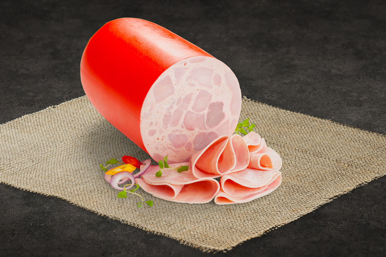 Mehrere Scheiben fein geschnittener Bierschinken mit leicht marmorierter Struktur, angerichtet auf einem Holzbrett mit Petersiliengarnitur – hochwertige, frische Wurstware für Brotzeit oder Frühstück.