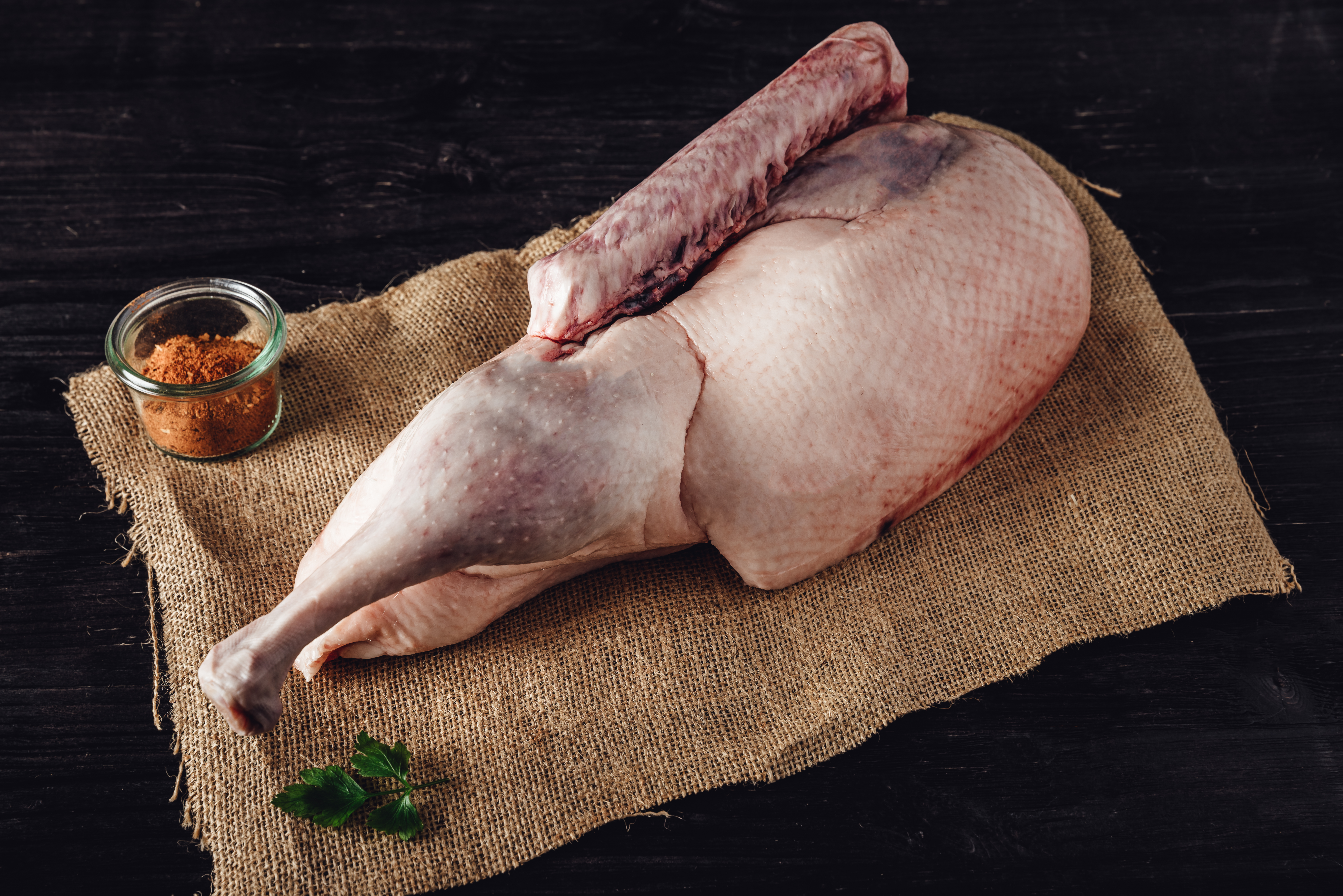 Halbe Oberpfälzer Weihnachtsgans knusprig gebraten auf traditioneller Servierplatte Halbe gebratene Oberpfälzer Weihnachtsgans mit knuspriger Haut, serviert auf einem weißen Teller mit kräftiger Bratensauce, dazu Apfelrotkohl und zwei Kartoffelklöße; traditionelles bayerisches Weihnachtsgericht auf rustikalem Holztisch angerichtet.