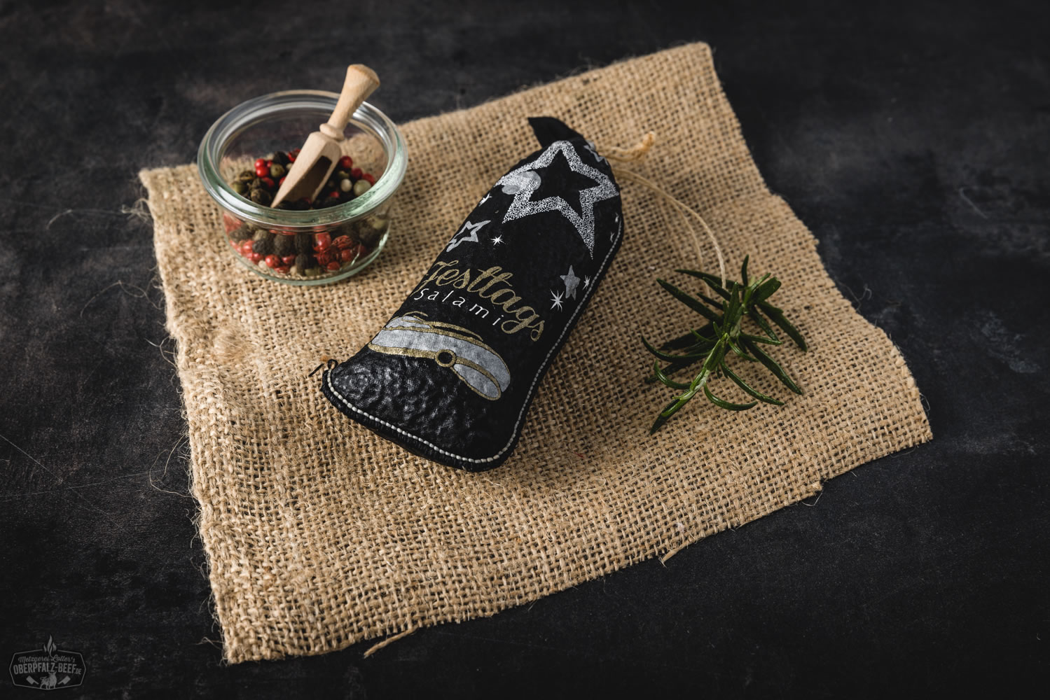 Festtagssalami aus 100 % regionalem Rindfleisch – Oberpfalz Beef Delikatesse Festtagssalami im Anschnitt auf Holzbrett angerichtet, dekoriert mit Rosmarinzweig und Pfefferkörnern – traditionelle Delikatesswurst aus der Oberpfalz, ideal für Festtage und Feinschmecker.