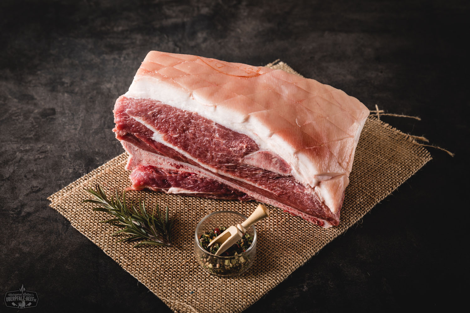 Schweineschulter vom Oberpfälzer Landschwein auf rustikaler Holzunterlage mit frischem Rosmarin garniert.