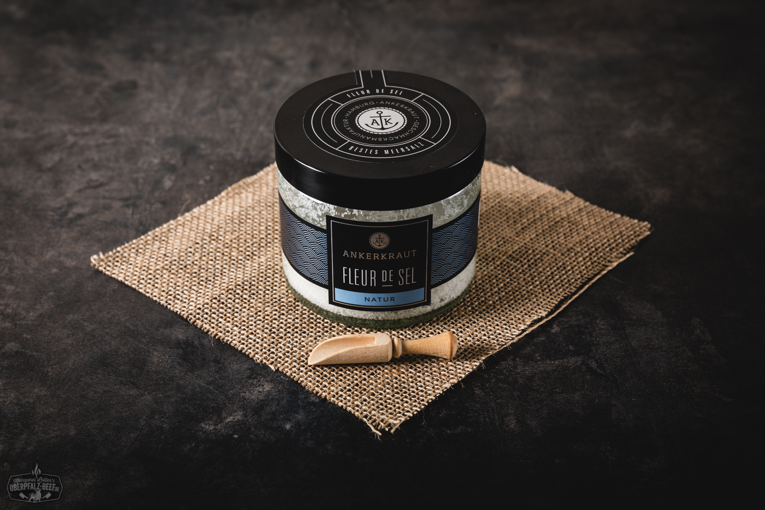 Fleur de Sel Natur von Ankerkraut – Edles Meersalz in Glasdose Glasgewürzstreuer mit naturbelassenem Fleur de Sel von Ankerkraut auf hellem Untergrund, Produktetikett deutlich lesbar, daneben grobe Salzflocken verstreut – hochwertige Meersalz-Zutat für Feinschmecker und BBQ-Liebhaber.
