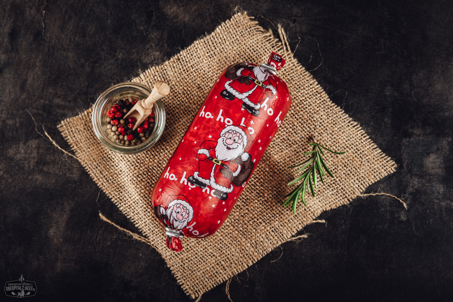 Nikolaus Salami Portionswurst – herzhafte Geschenkidee zu Weihnachten Nikolaussalami in Portionsgröße auf dunklem Hintergrund arrangiert, dekorativ mit Tannenzweigen, Gewürzen und weihnachtlicher Schleife präsentiert – weihnachtliche Geschenkidee mit rustikaler Wurst aus der Oberpfalz.