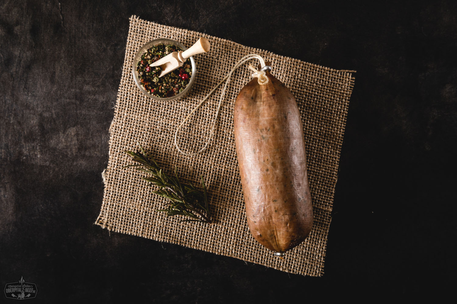 Original Oberpfälzer Bauernleberwurst schwarzgeräuchert – traditionelle Hausmacher-Wurst aus Bayern Schwarzgeräucherte Oberpfälzer Bauernleberwurst als aufgeschnittene Wurstscheiben und im Naturdarm, angerichtet auf einem Holzbrett mit frischem Brot, Zwiebelringen, Gurke und Petersilie – traditionelle bayerische Spezialität rustikal in Szene gesetzt.