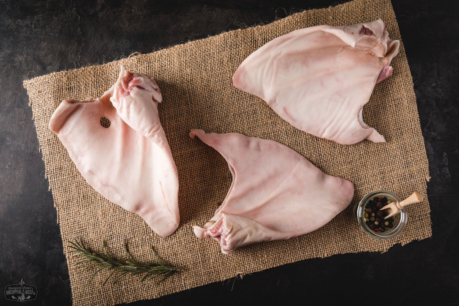 Ohren vom Oberpfälzer Landschwein roh – Regionales Schweinefleisch für besondere Rezepte Rohe Schweineohren vom Oberpfälzer Landschwein, frisch zugeschnitten und auf einem dunklen Brett angerichtet, ideal für Zubereitung oder Feinkost – regionale Fleischspezialität aus Bayern.