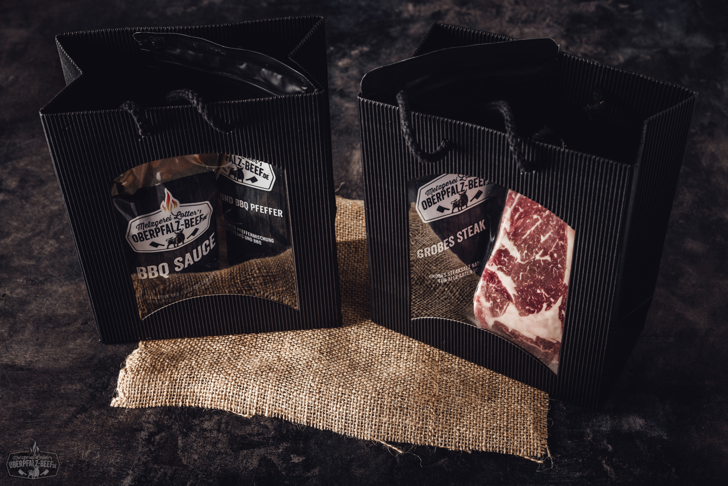 Weihnachtlich dekorierte Papiertüte mit „Oberpfalz Beef“-Logo, gefüllt mit regionalen Fleischspezialitäten, auf Holztisch vor Tannenzweigen und roten Christbaumkugeln – stimmungsvolle Präsentation regionaler Feinkost zu Weihnachten.