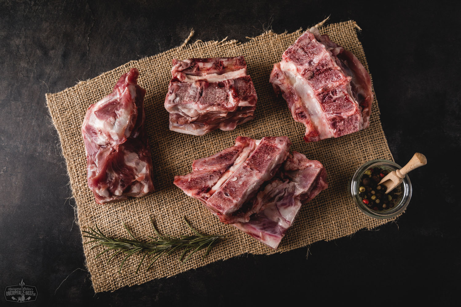 Frisches Schweineklein vom Oberpfälzer Landschwein – regionales Fleisch in höchster Qualität Frisch portioniertes Schweinefleisch vom Oberpfälzer Landschwein auf Holzbrett, dekoriert mit rosa Pfefferkörnern, Knoblauchzehen, Rosmarinzweigen und einer roten Chilischote – hochwertige Fleischspezialität für bewusste Genießer.