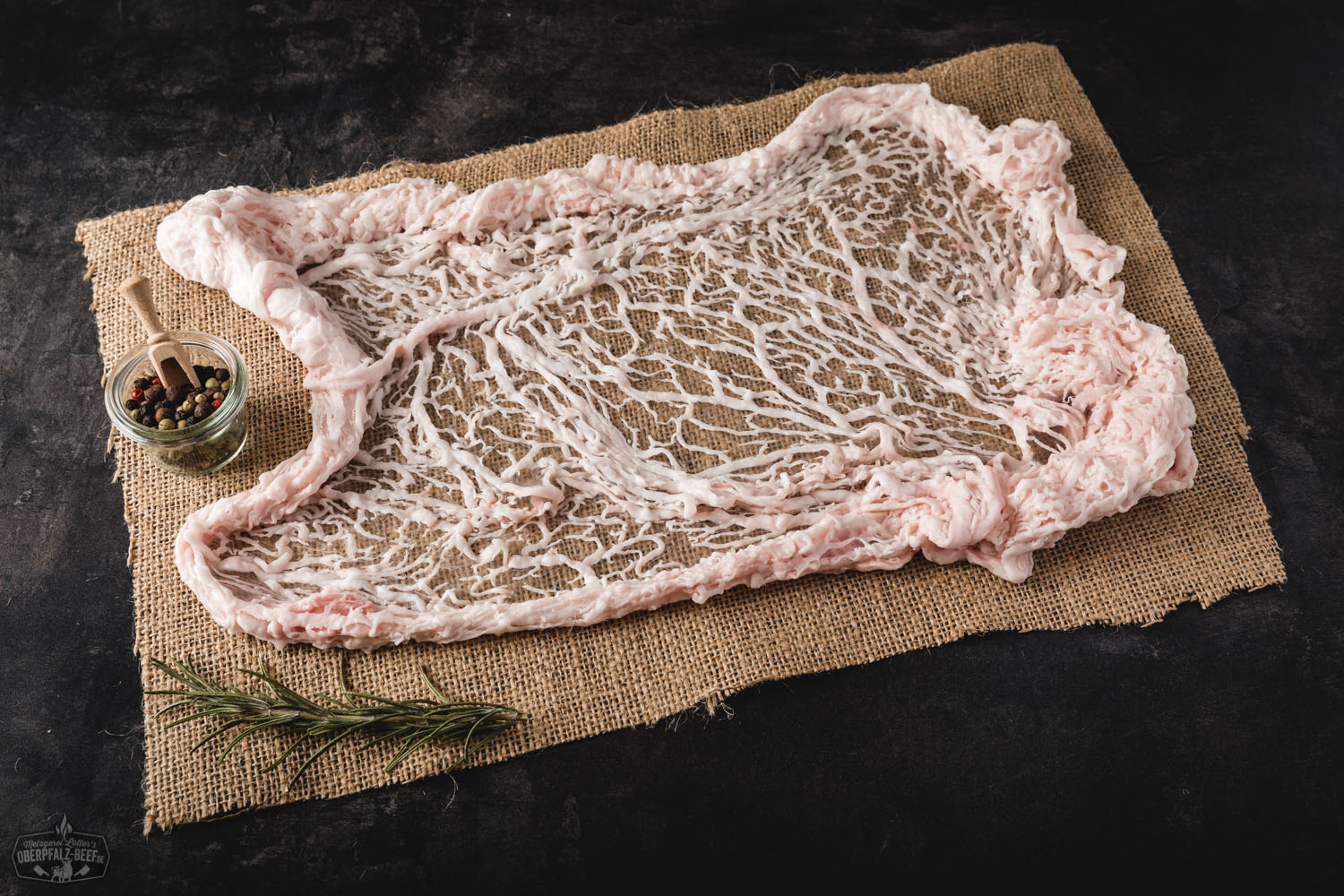 Netz vom Oberpfälzer Landschwein auf Holzbrett – regionales Schweinefleisch in Premiumqualität Rohes Netz vom Oberpfälzer Landschwein auf dunklem Untergrund, detailreich mit sichtbarer Fettmarmorierung und grobmaschiger Netzhülle präsentiert – hochwertige Fleischspezialität aus der Region Oberpfalz.
