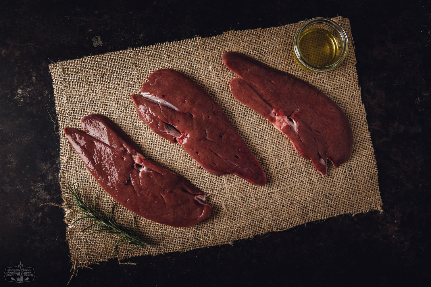 Leber in Scheiben vom Oberpfälzer Landschwein – Frisch und regional kaufen Roh geschnittene Schweineleber vom Oberpfälzer Landschwein, frisch angerichtet auf Holzbrett mit dunklem Hintergrund, detailreich sichtbare Fleischstruktur und kräftige Farbe, Darstellung hochwertiger regionaler Fleischqualität für bewusste Ernährung.