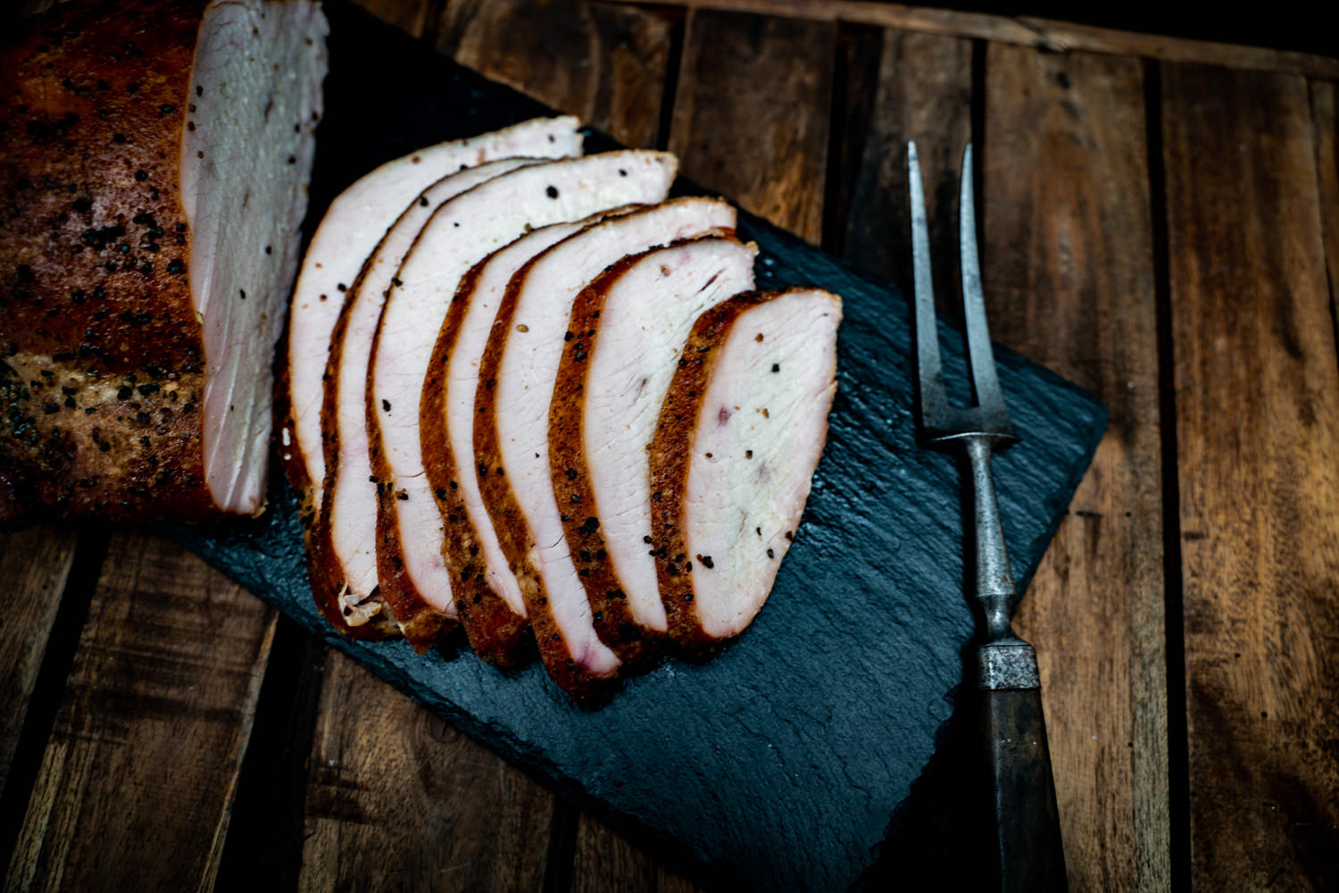 Brustfilet von der Oberpfälzer Bauernpute – Frisches Putenfleisch direkt vom Bauernhof Rohes Brustfilet von einer Oberpfälzer Bauernpute auf dunklem Untergrund, von frischen Kräutern, Gewürzen und Gemüse wie Knoblauch und Tomaten umgeben – hochwertiges Geflügelfleisch aus regionaler Aufzucht.