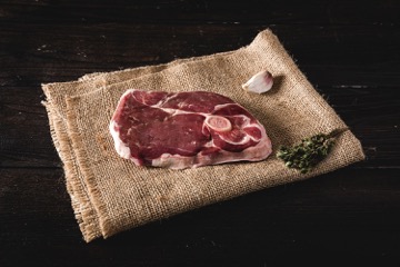 Steaks aus der Lammkeule vom Juradistl-Lamm frisch gegrillt auf Holzbrett Aufgeschnittener, saftiger Lammlachs-Rollbraten mit Kräuterkruste, perfekt gegart im Sous-vide-Verfahren, angerichtet auf einem Holzbrett mit Rosmarinzweigen und Gewürzen – hochwertiges Premium-Lammfleisch aus der Oberpfalz.