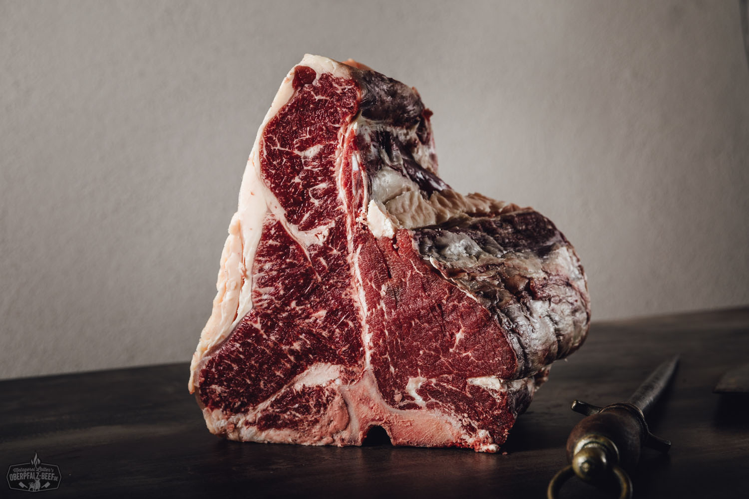 Porterhouse Steak vom Oberpfalz-Rind zum Selberreifen – Premium Dry Aged Beef Rohes Porterhouse-Steak vom Oberpfalz-Rind auf dunklem Untergrund, mittig platziert, stark marmoriert mit sichtbarem T-Knochen, hochwertiges Fleischstück zum Selberreifen – Premium-Beef aus Bayern, optimal für Grill oder Dry Ager.