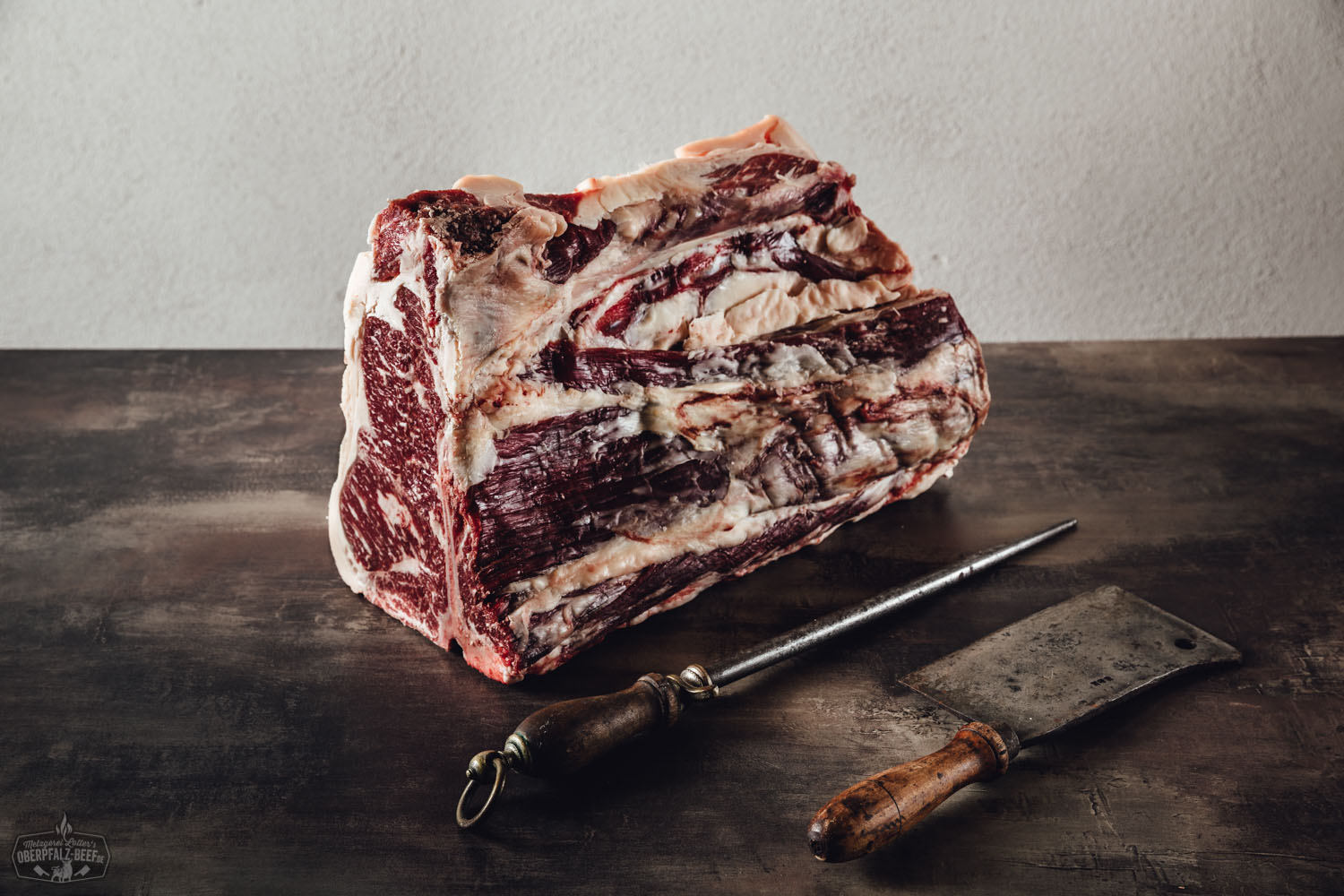 Trocken gereiftes T-Bone- und Porterhouse-Steak vom Oberpfalz-Rind auf dunklem Untergrund, roh, sichtbar marmoriert, mit kräftigem Fettrand – hochwertiges Dry Aged Beef als Premium-Grillfleisch für Steak-Liebhaber.