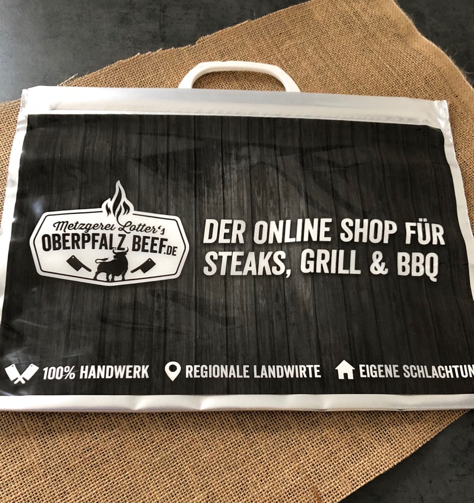 Große schwarze Kühltasche mit dem weißen Logo von Oberpfalz-Beef, stehend auf hellem Hintergrund; die Tasche hat stabile Tragegriffe, einen Reißverschluss oben und ist für den Transport von gekühltem Fleisch geeignet.
