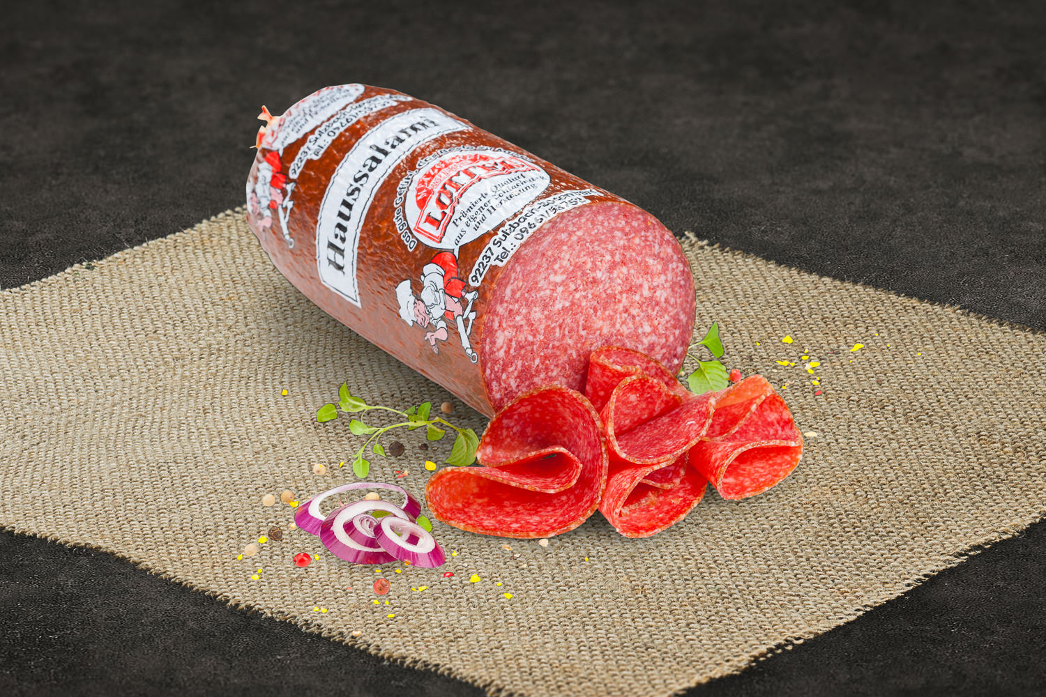 Geschnittene Haussalami aus Rindfleisch auf einem Holzbrett angerichtet, mit frischen Kräutern garniert – traditionelle, rustikale Wurstware aus Bayern.