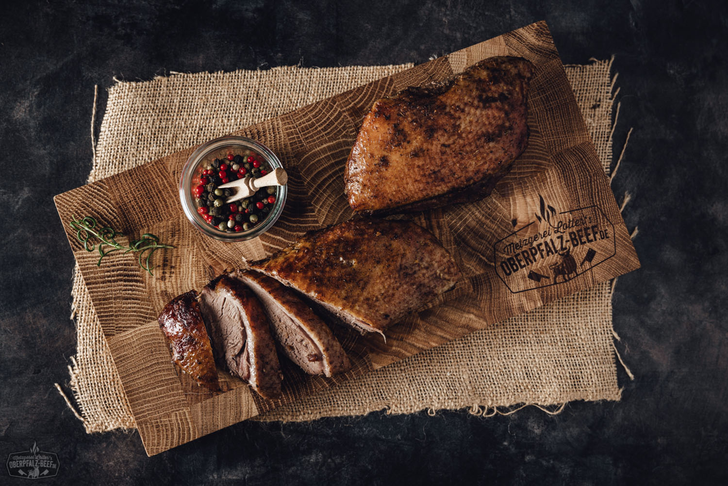Sous-vide Gänsebrustfilet ohne Knochen – zart vorgegart und servierfertig Vorgegartes Gänsebrustfilet ohne Knochen, zartrosa gegart, mit knuspriger Haut, auf einem Holzbrett angerichtet, umgeben von frischen Kräutern, Orangenscheiben und Bratensauce – hochwertiges Sous-vide-Fleisch aus der Oberpfalz.