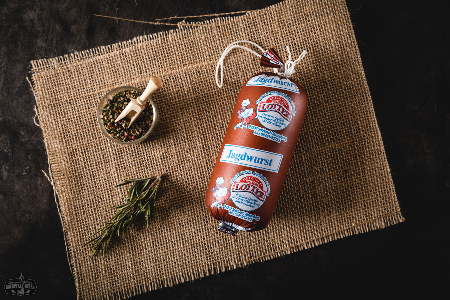 Mehrere vakuumverpackte Portionsstücke Jagdwurst liegen auf einem dunklen Untergrund; jede Wurst ist mit einem weißen Etikett versehen, auf dem "Jagdwurst" und das Logo von Oberpfalz-Beef zu lesen sind.