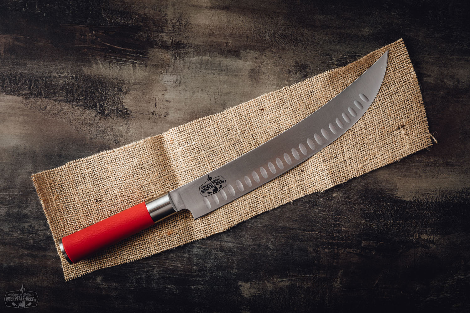 Grillmesser Dick Red Spirit mit rotem Griff – Profi Küchenmesser für Fleisch und BBQ Grillmesser mit rotem Griff aus der „Red Spirit“-Serie von Dick, Modell „Hecktor“, liegt auf dunklem Untergrund – hochwertiges, scharfes BBQ-Messer für Fleisch, ideal für Barbecue und Grillfans.