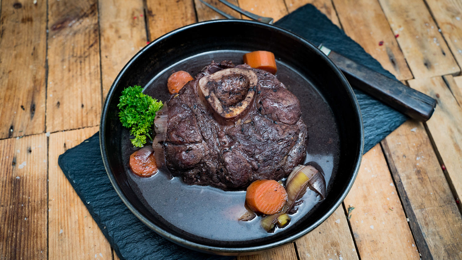 Ossobuco vom Oberpfälzer Milchkalb auf rustikalem Holzbrett – zart geschmorter Kalbsbeinscheiben-Genuss Ossobuco vom Oberpfälzer Milchkalb auf einem rustikalen Holzbrett angerichtet, begleitet von frischen Kräutern und Gemüse.